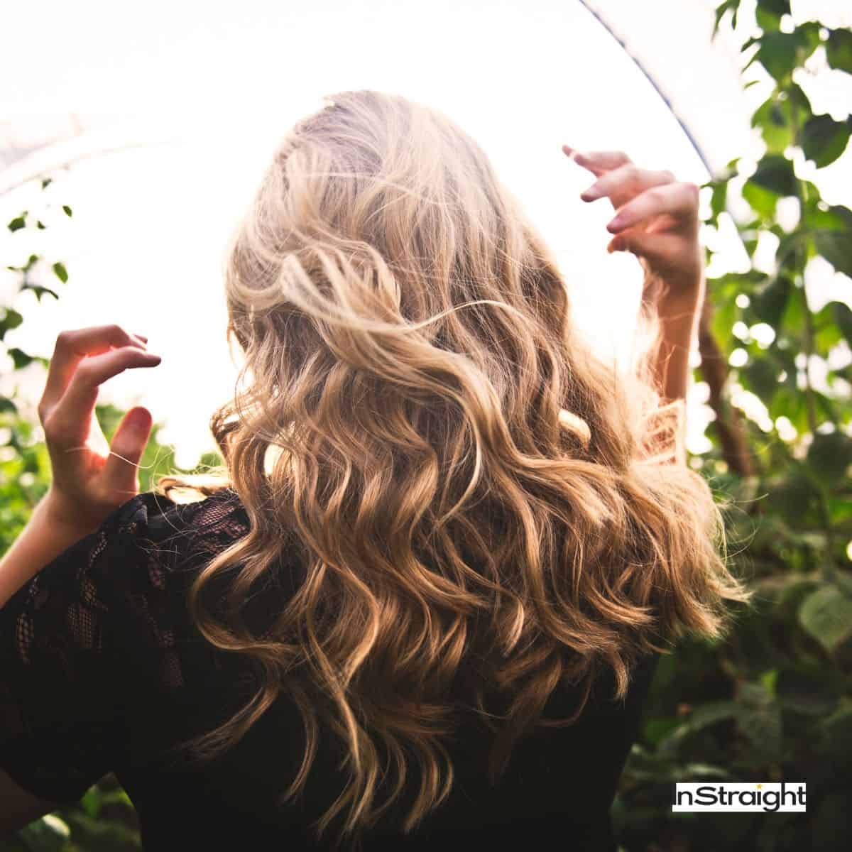 lady with curly hair under the sun but does the sun damage the hair?